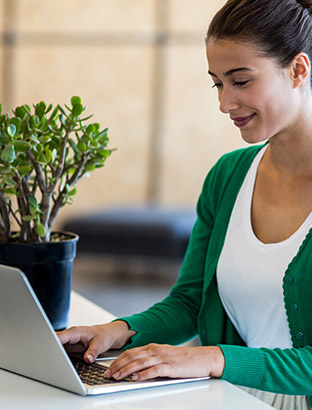 Happy lady with a plant on her desk